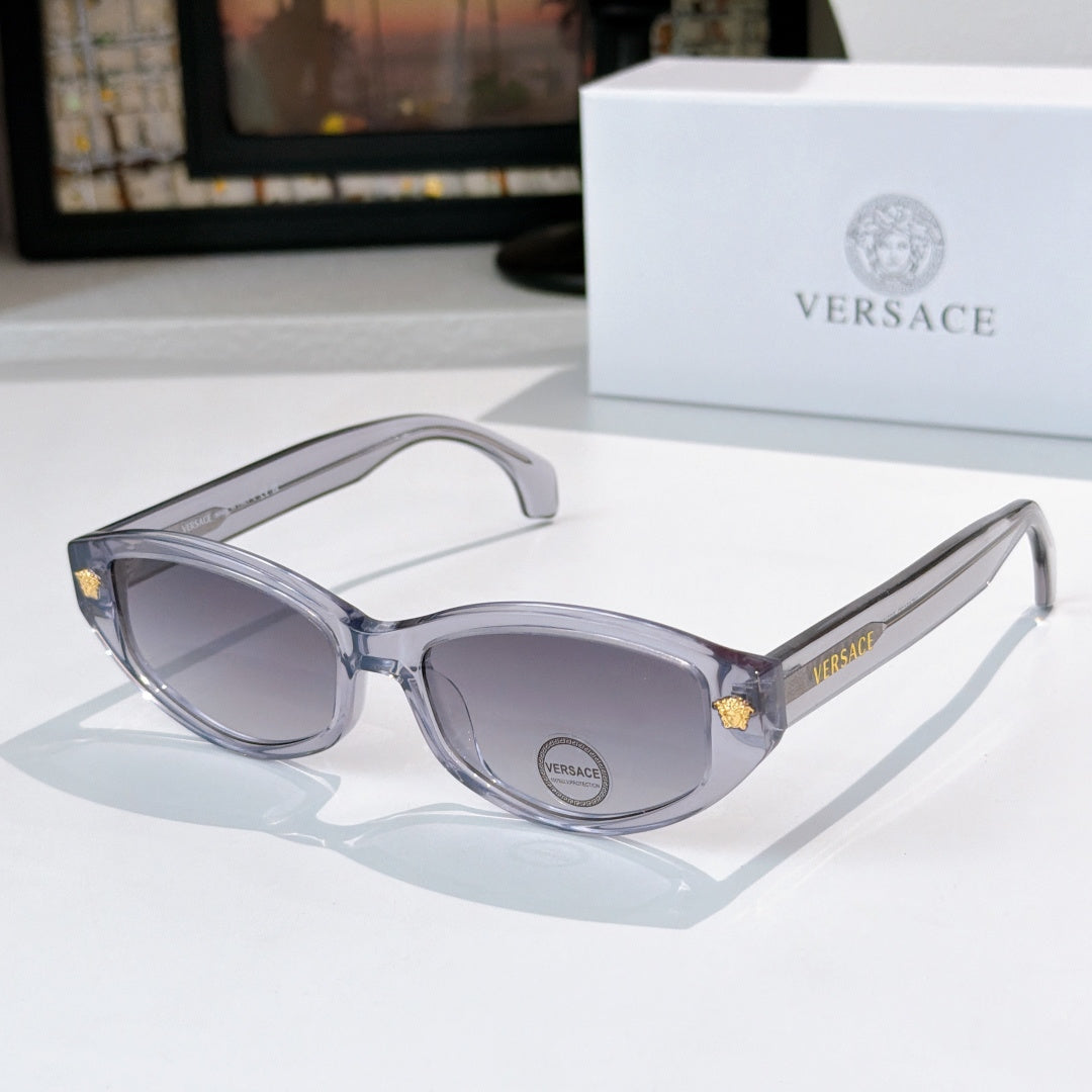 Silver cat-eye sunglasses with gray lenses and gold emblem on temples