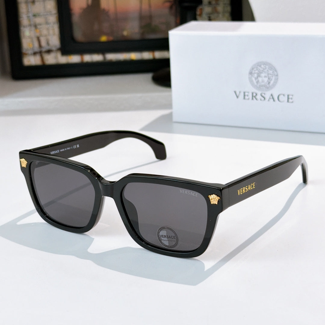 Black cat-eye sunglasses with dark lenses and gold VERSACE logo on temple