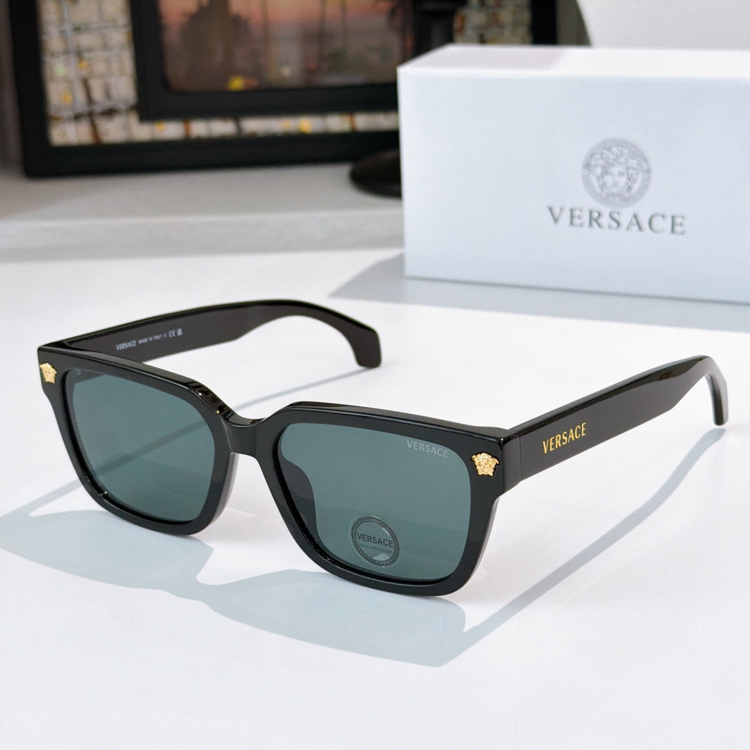 Black cat-eye sunglasses with dark lenses and gold logo accents