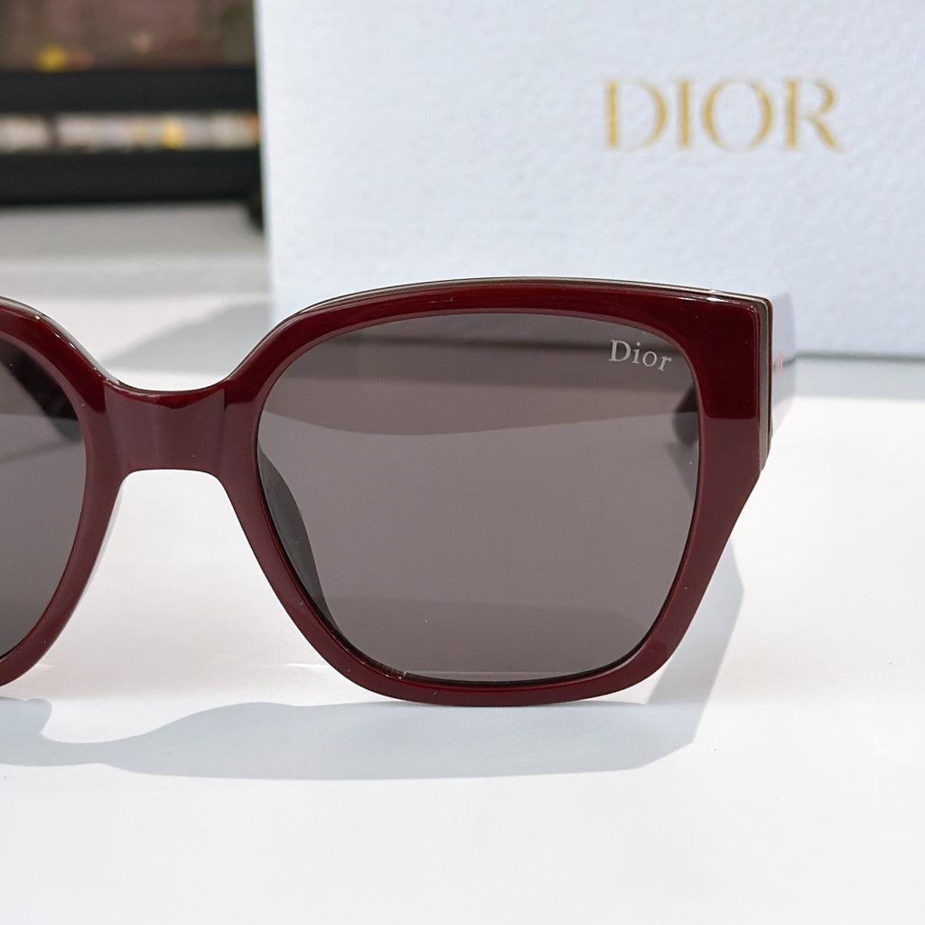 Dior sunglasses close-up with burgundy frames and gray tinted lenses