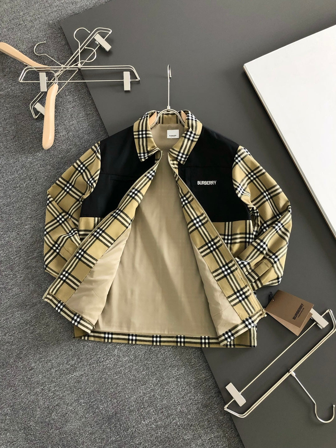 Long-sleeve zip-up jacket with black and beige plaid panels and hoodless stand collar.