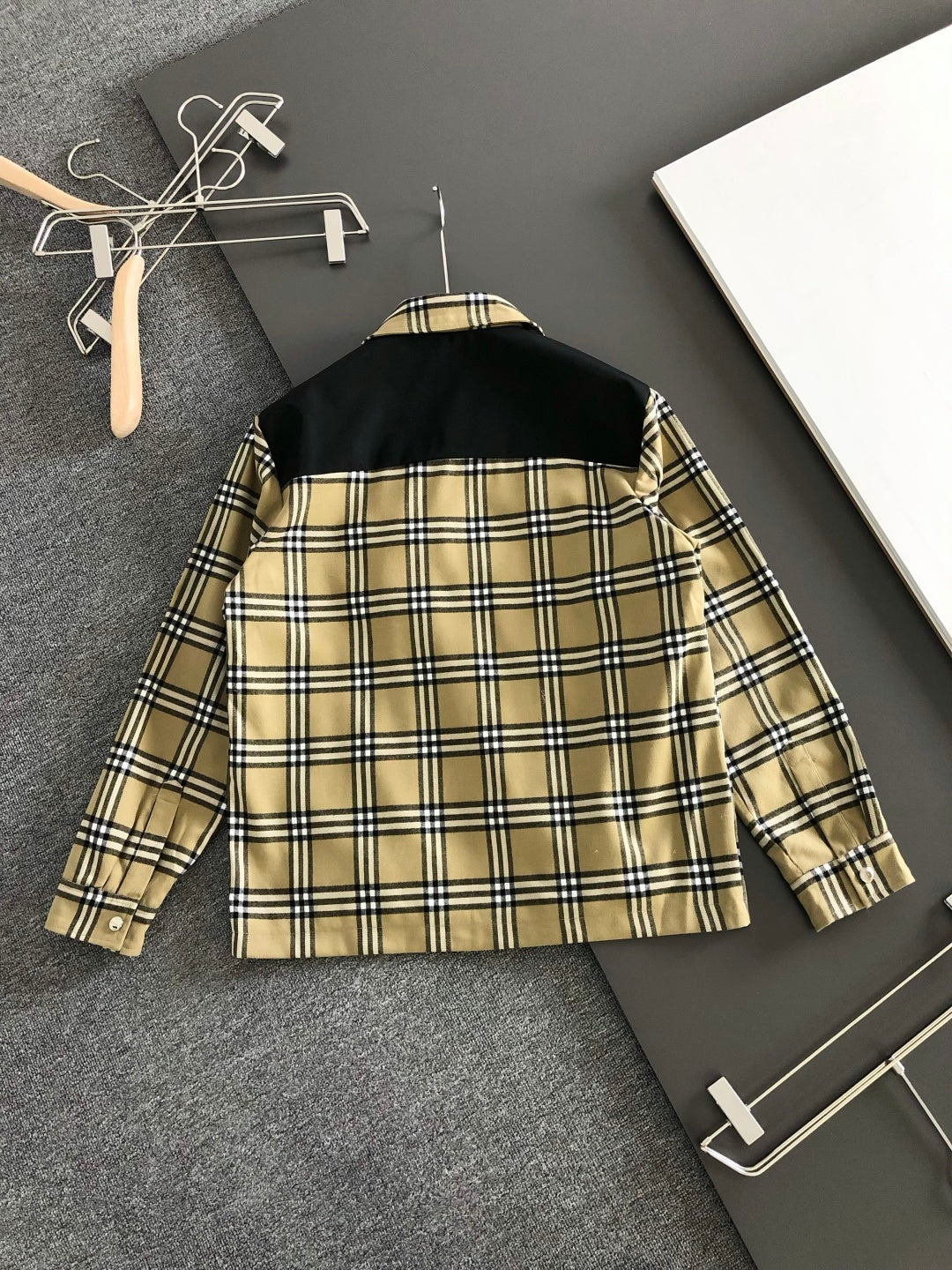 Back view of long-sleeve plaid jacket with black and beige check pattern across yoke.