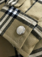 Close-up of plaid fabric cuff with a small metal button and stitched seam.