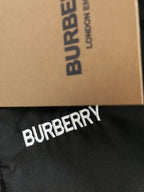 “BURBERRY” logo print on black fabric of a plaid collar jacket.
