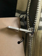 Close-up of zipper and pull on plaid jacket; metal zip teeth and fastening tab.