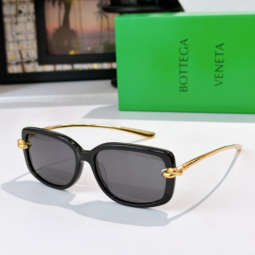 Black cat-eye sunglasses with gold-tone hinges and dark tinted lenses.
