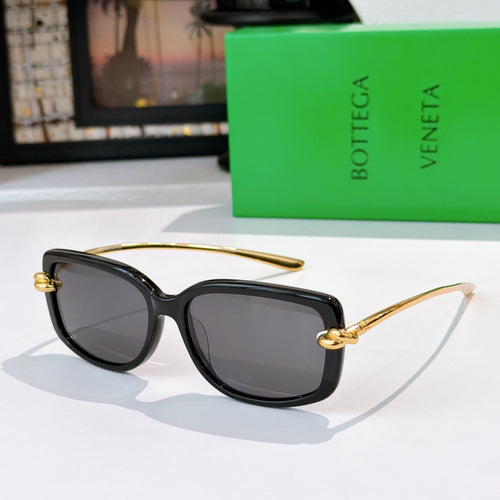 Black cat-eye sunglasses with gold-tone hinges and dark tinted lenses.