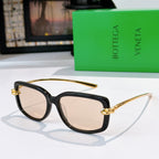 Black cat-eye sunglasses with gold-tone hardware and light beige lenses.