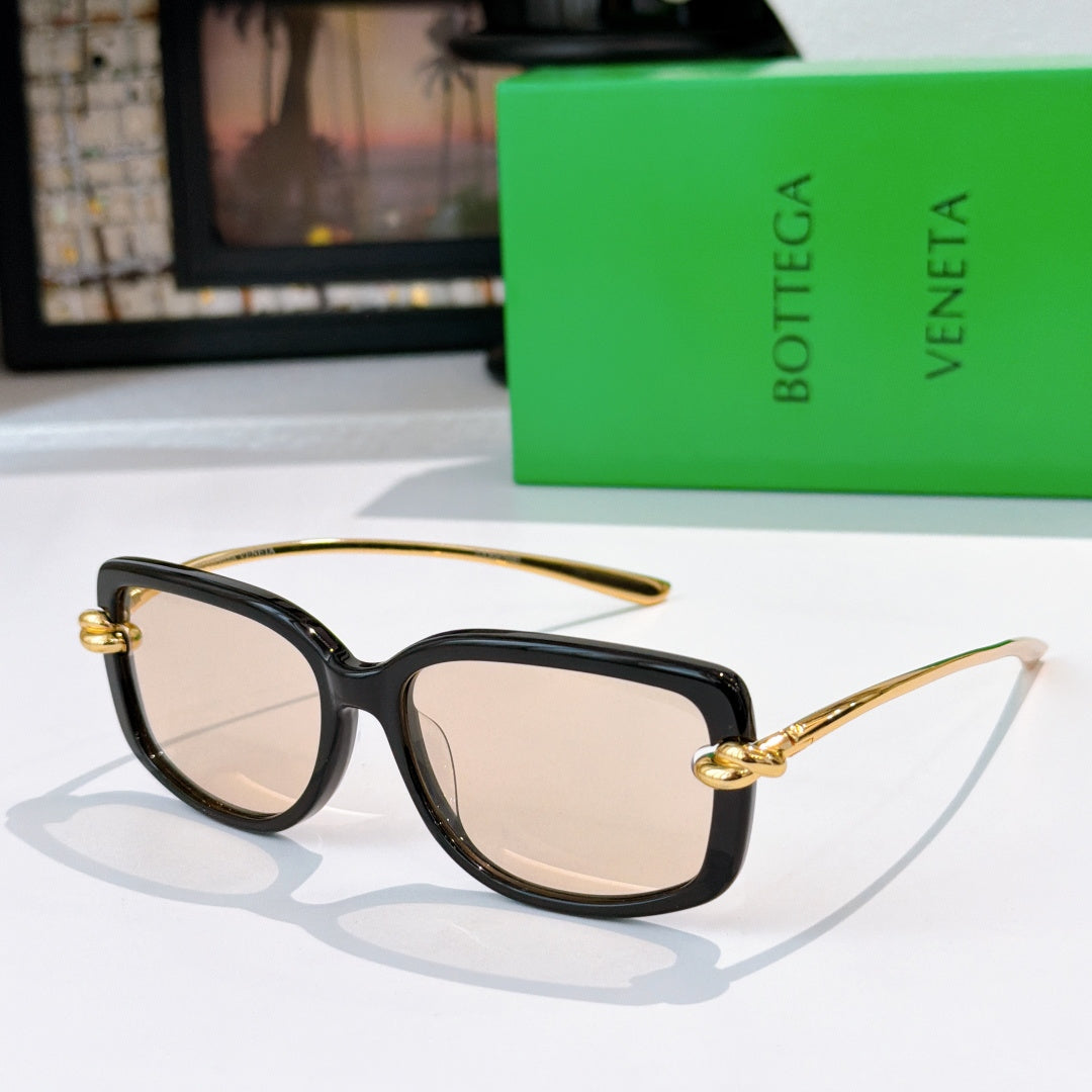 Black cat-eye sunglasses with gold-tone hardware and light beige lenses.