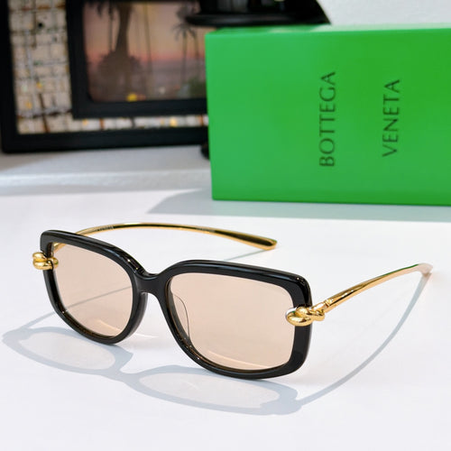 Black cat-eye sunglasses with gold-tone hardware and light beige lenses.