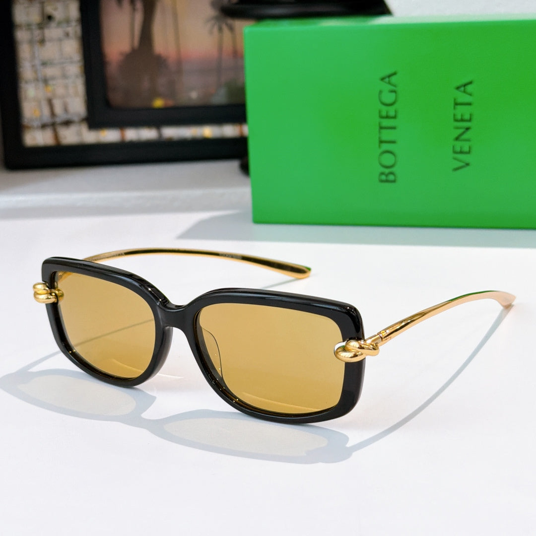 Black cat-eye sunglasses with gold-tone accents and amber-tinted lenses.