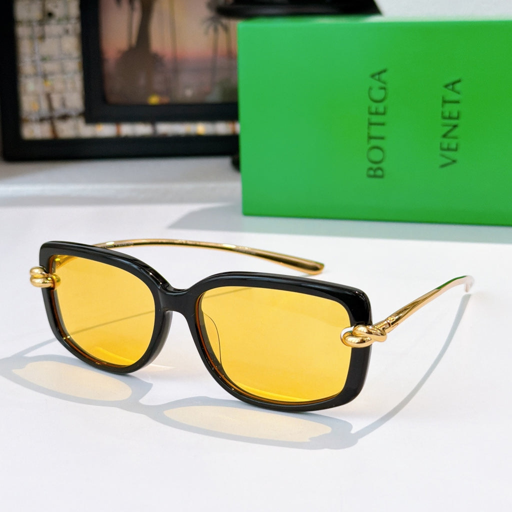 Black cat-eye sunglasses with gold-tone hardware and yellow tinted lenses.