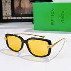 Black cat-eye sunglasses with gold-tone hardware and yellow tinted lenses.