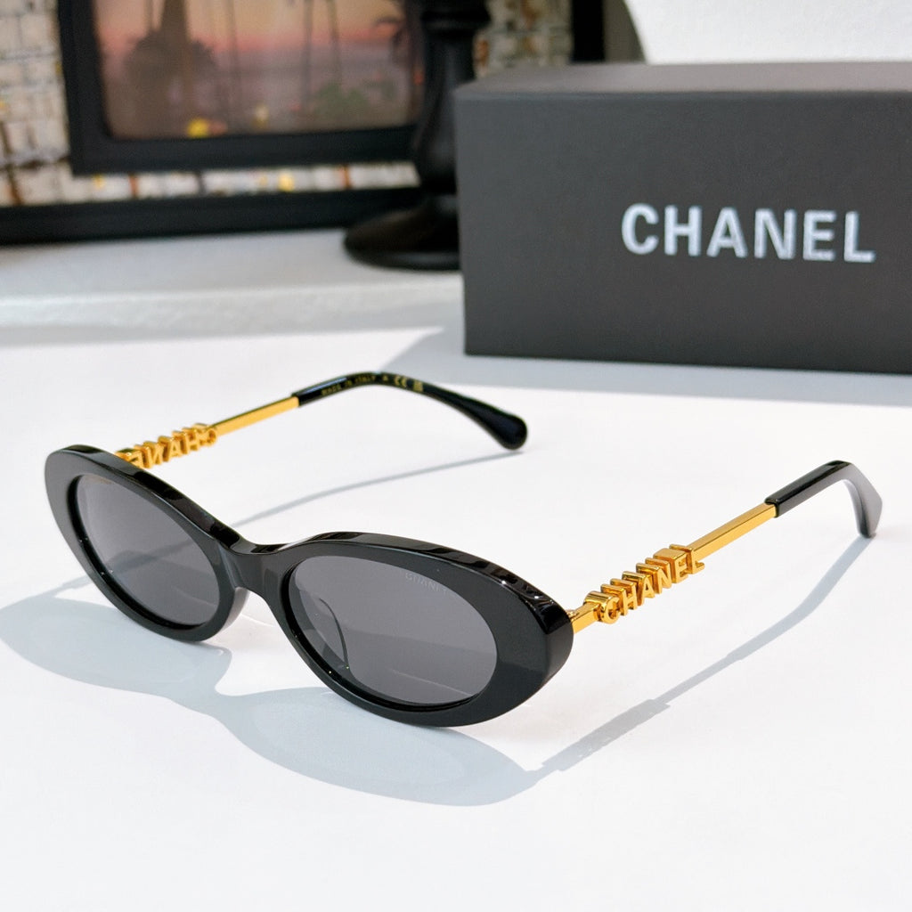 Chanel sunglasses with dark frames and gray tinted lenses, gold chain arms.