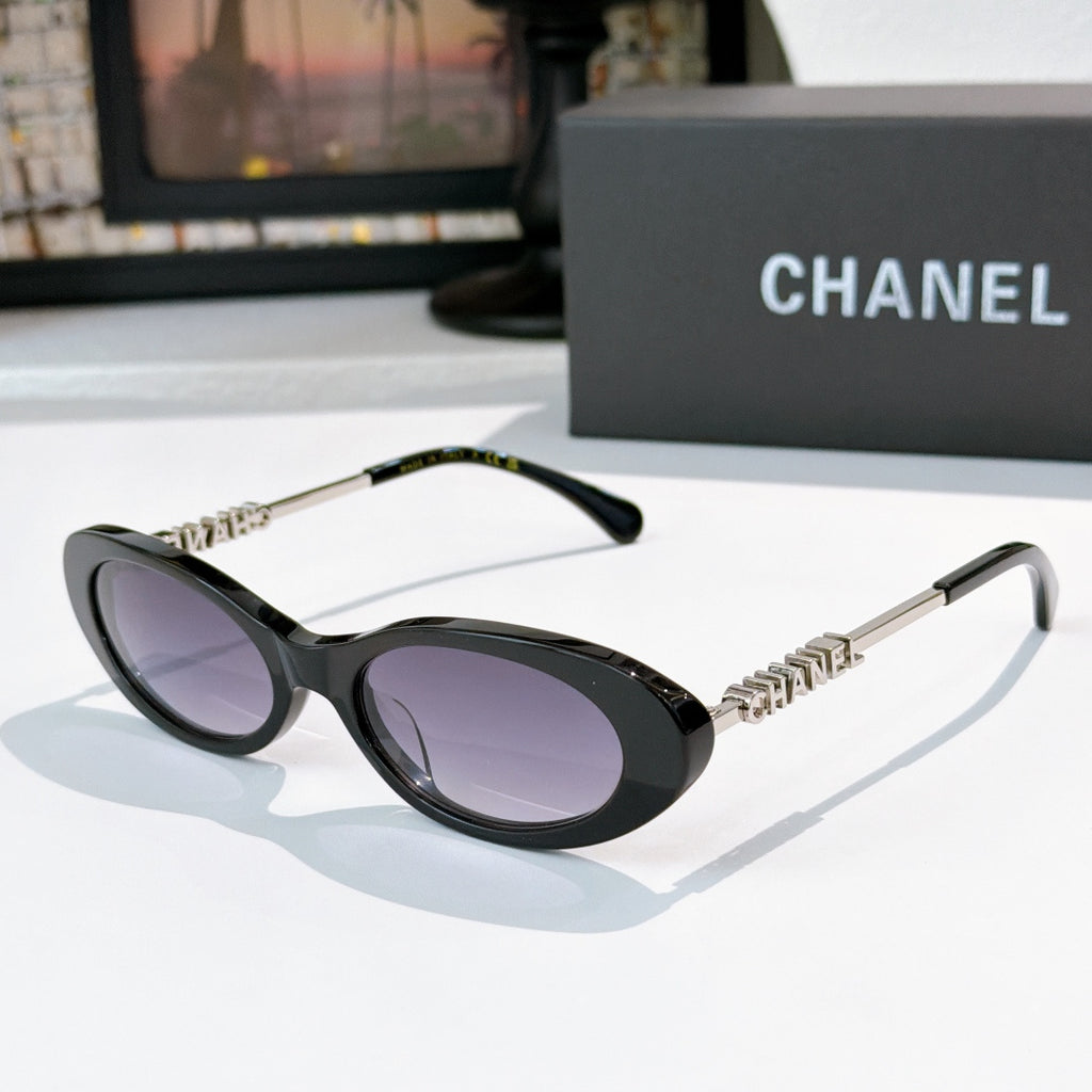Chanel sunglasses with black frames and purple tinted lenses, metallic chain arms.