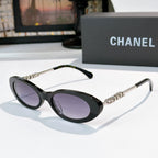 Chanel sunglasses with black frames and purple tinted lenses, metallic chain arms.