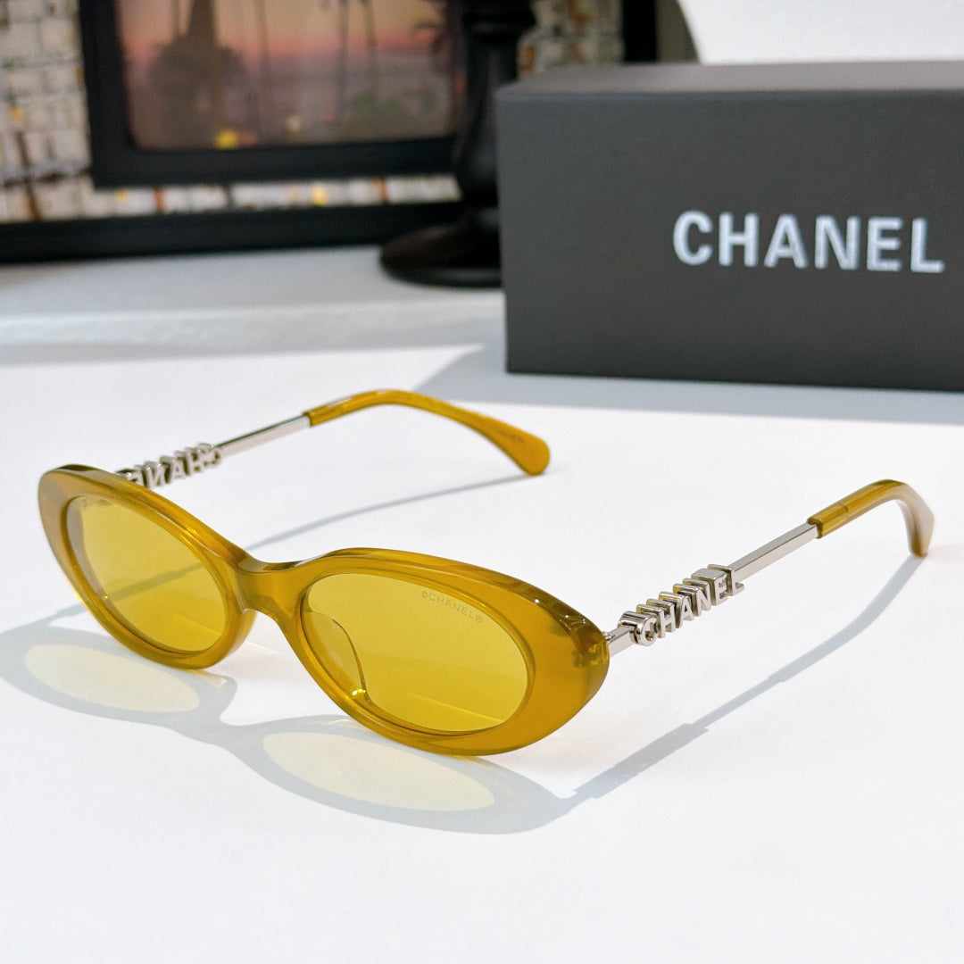Chanel sunglasses with yellow frames and amber tinted lenses, metallic chain arms.