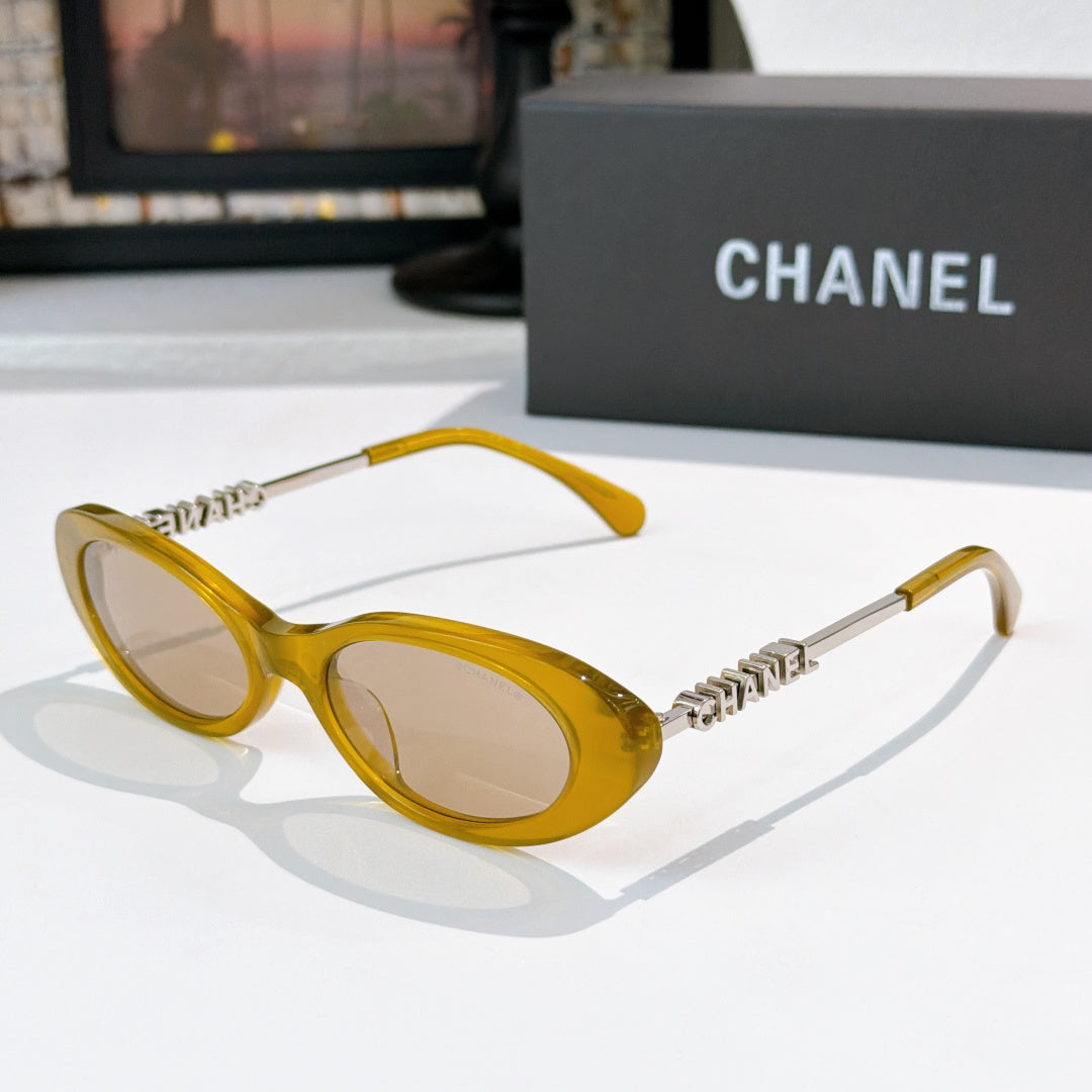 Chanel sunglasses with amber yellow frames and tinted amber lenses, metallic chain arms.