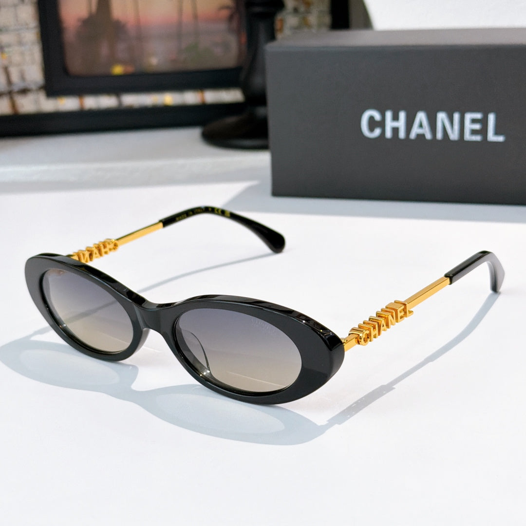 Chanel sunglasses with black frames and light tinted lenses, gold chain arms.