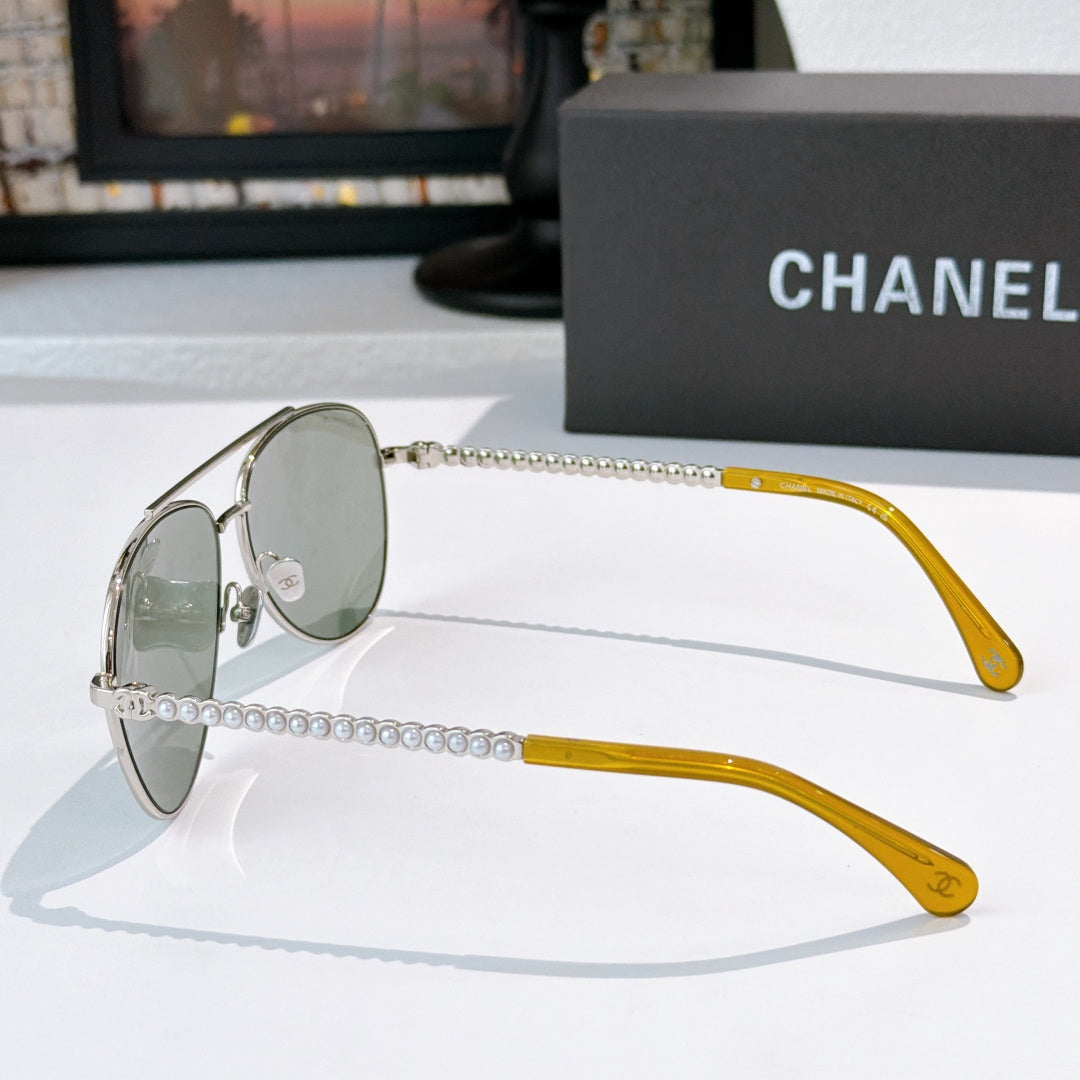Aviator sunglasses with silver frame, green mirrored lenses, and chain temple arms