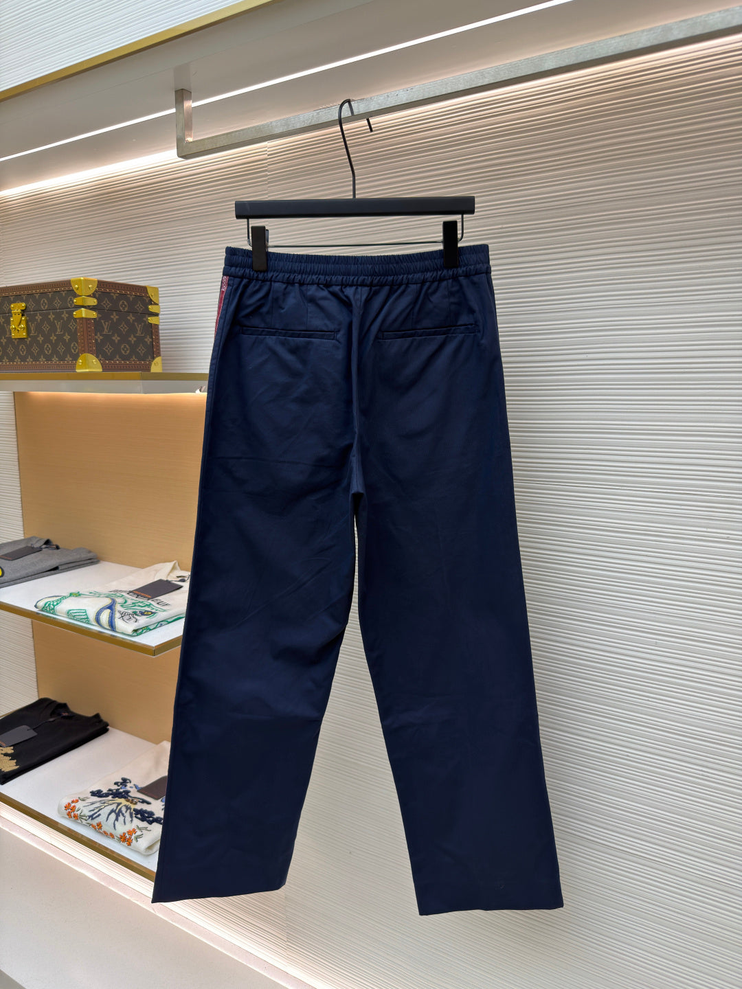 Navy pants on hanger with elastic waistband, side pockets, and red side stripe