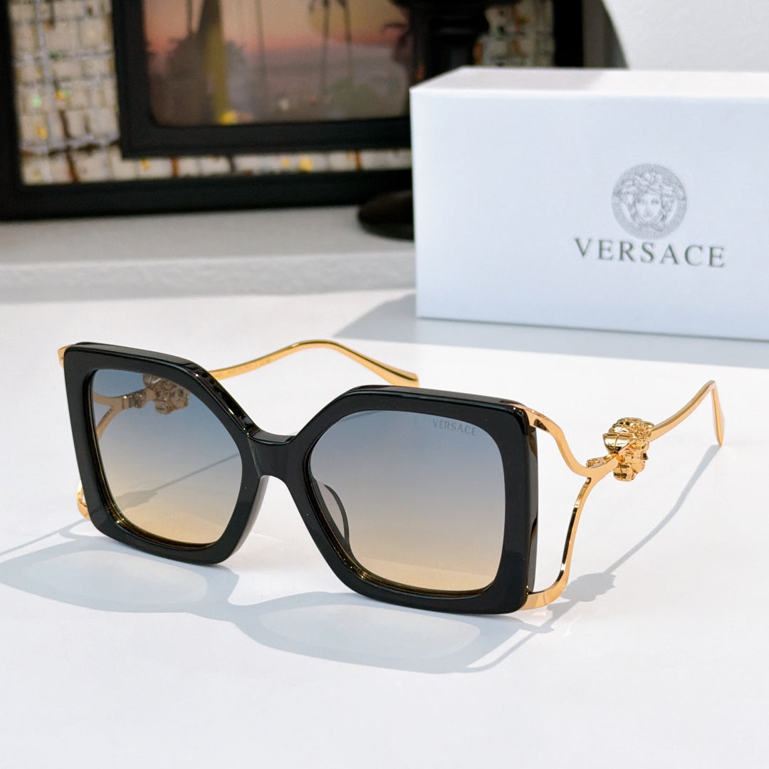 Oversized square sunglasses with black frame, dark lenses, gold lion temple detail.