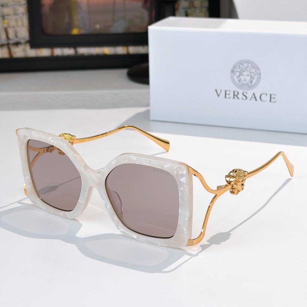 Square sunglasses with translucent light frame, dark lenses, gold lion temple detail.