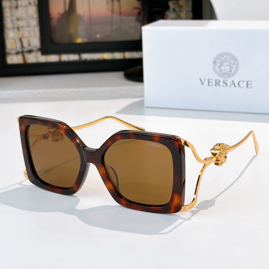 Square sunglasses with tortoiseshell frame, amber-brown lenses, gold lion temple detail.