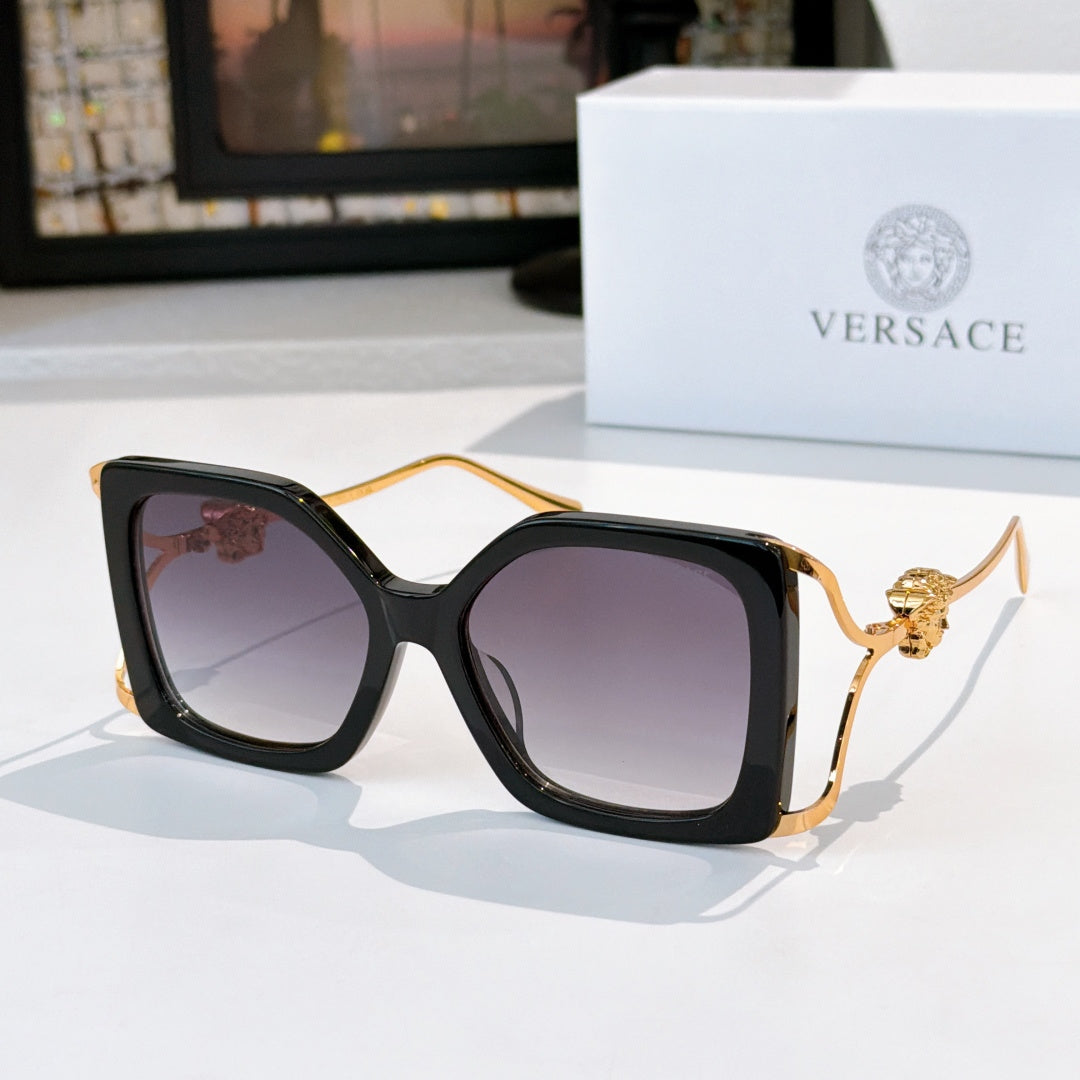 Oversized square sunglasses with black frame, dark lenses, gold lion temple detail.