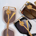 Pair of square sunglasses with gold accents, gold lion emblems, translucent and dark lenses.