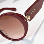 Close-up burgundy sunglasses with gold lion emblem and BVLGARI logo on temple