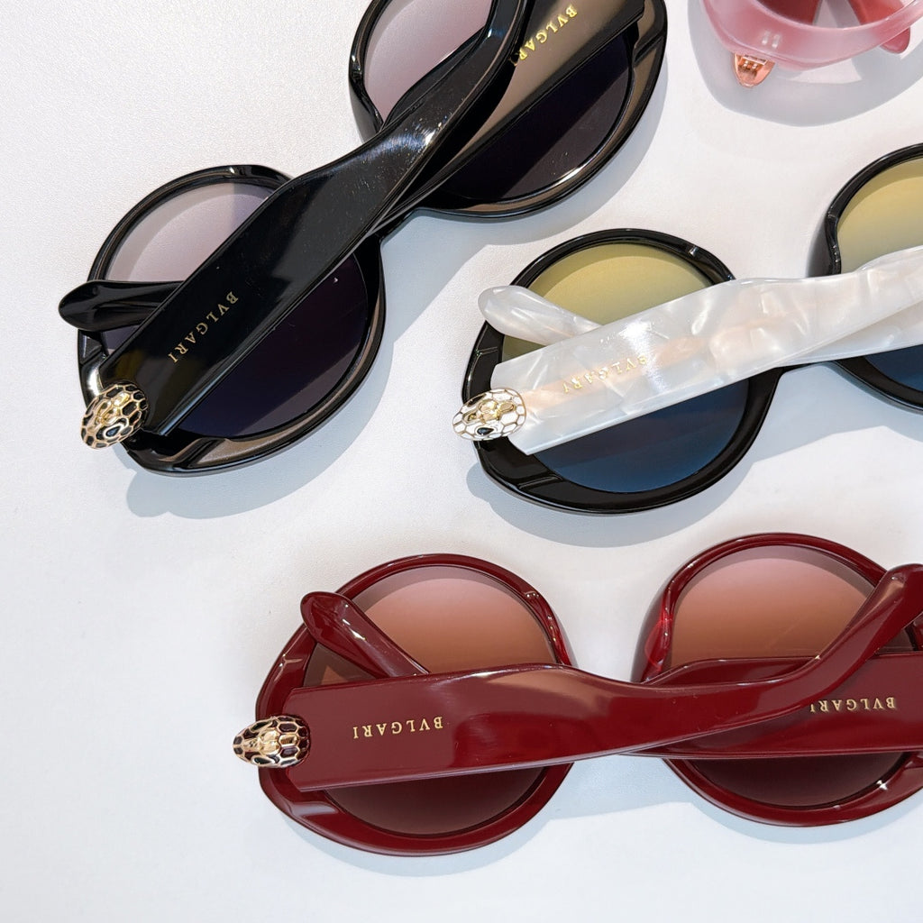 Assorted sunglasses laid out, black and red pairs with BVLGARI logos on temples