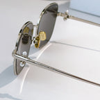 Silver-tone sunglasses side view with engraved temple and dark tinted lens