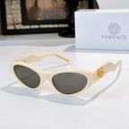 Cream cat-eye sunglasses with dark lenses and gold temple emblem