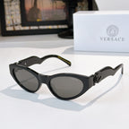 Black cat-eye sunglasses with dark lenses and gold logo hardware