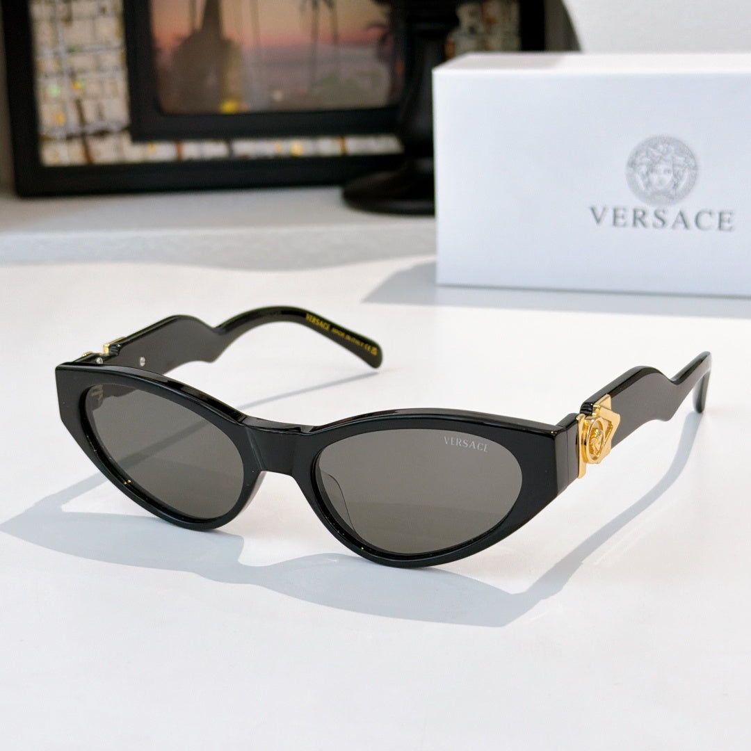 Black cat-eye sunglasses with dark lenses and gold temple emblem