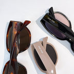 Assorted cat-eye sunglasses in black, tortoise, and beige with dark lenses