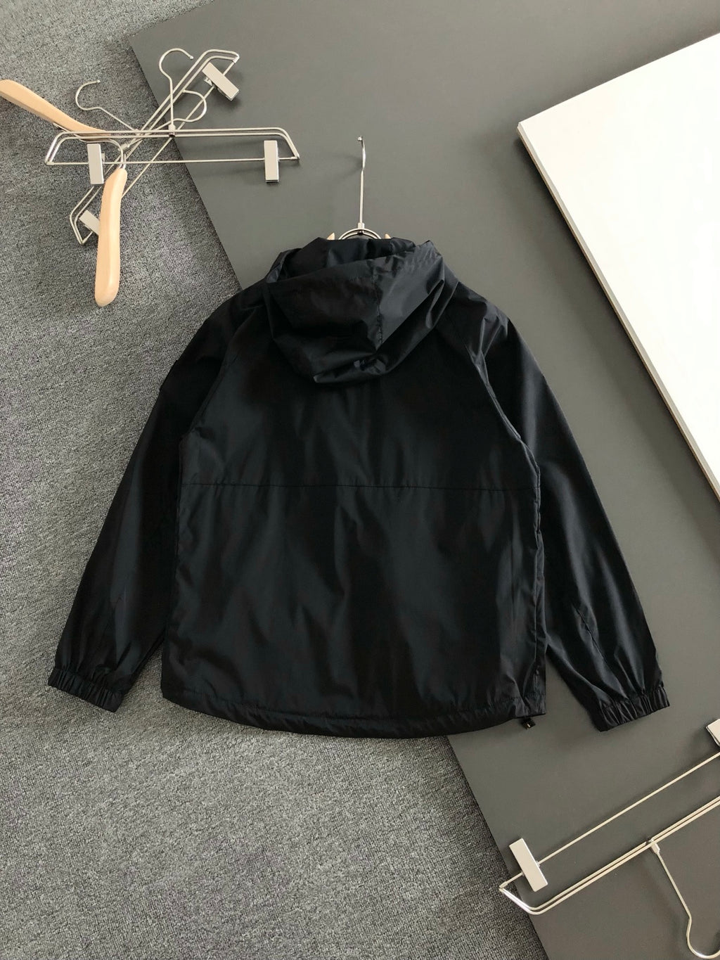 Black hooded long jacket back view with gathered collar and hood opening