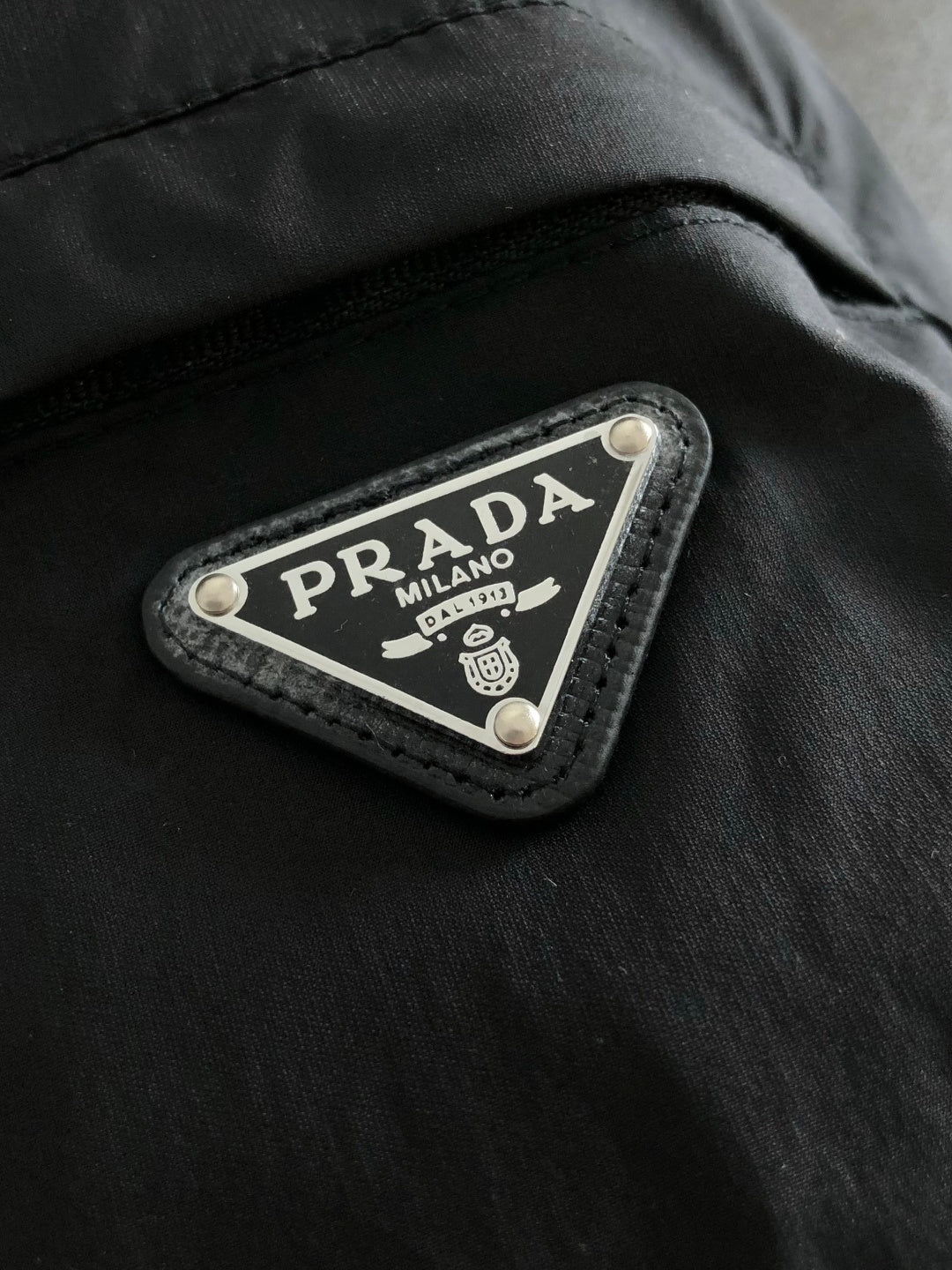 Prada Milano brand patch on black jacket seam