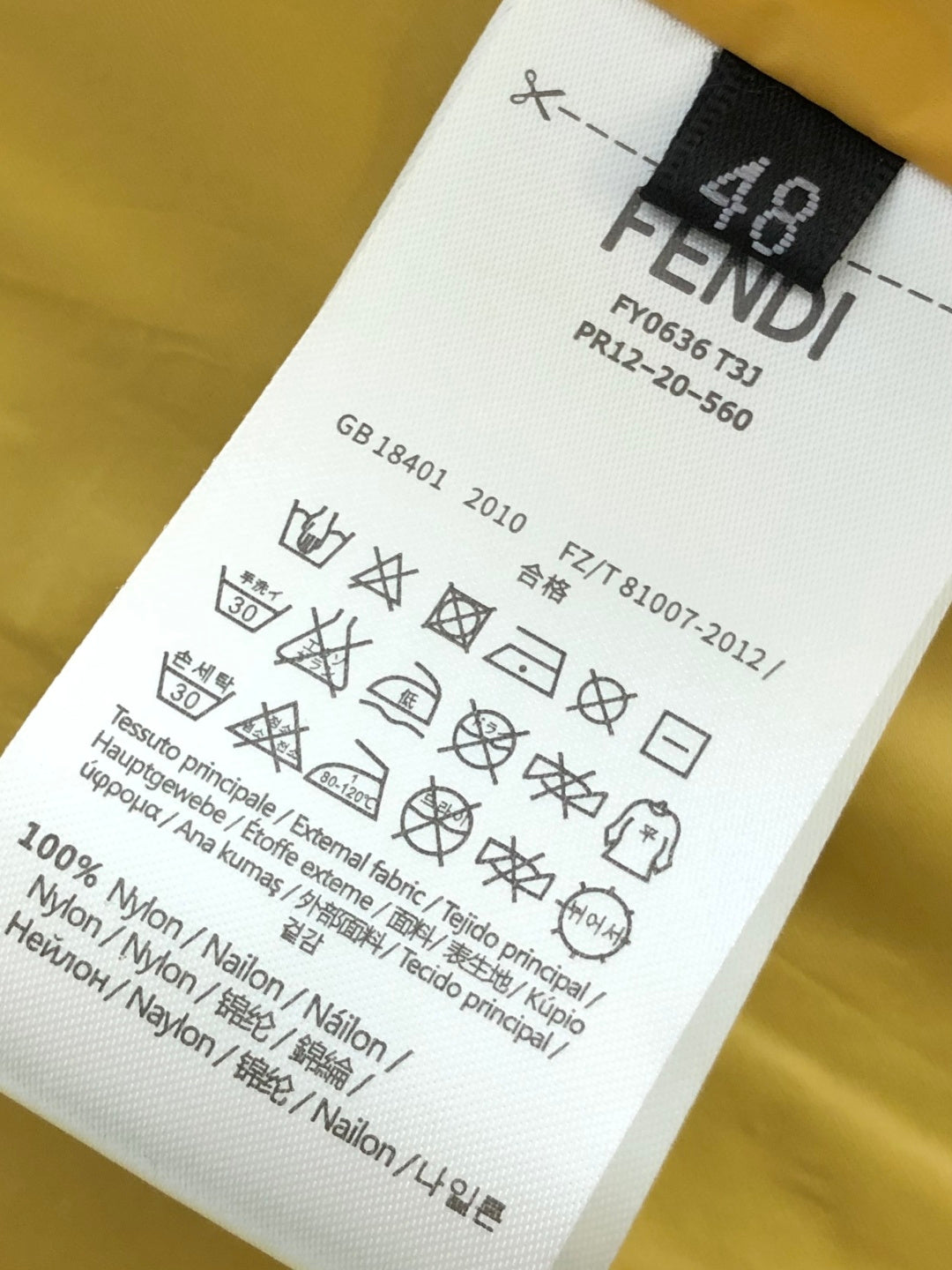 Yellow garment care label with FENDI ROMA text and washing symbols