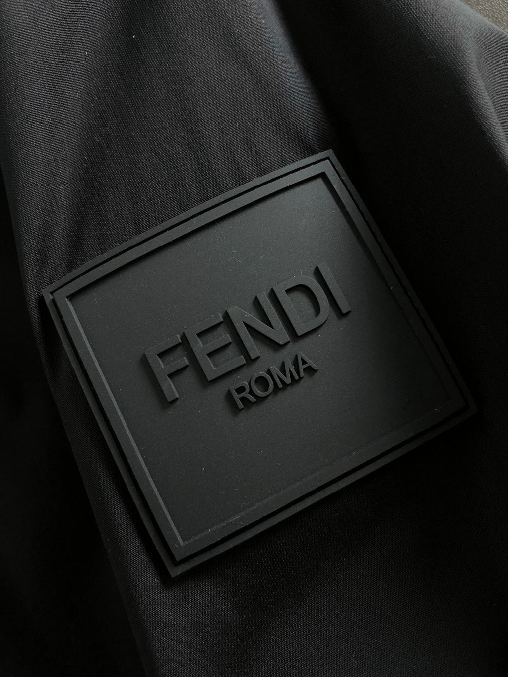 Black jacket fabric with embossed FENDI ROMA label patch