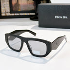 Sunglasses with black frames and gray-tinted lenses, Prada logo on temple
