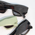 Close-up of sunglasses frames with Prada temple details: black and pale green