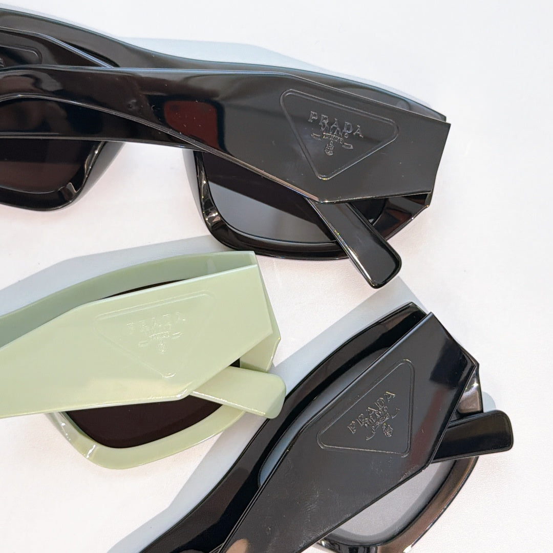 Close-up of sunglasses frames with Prada temple details: black and pale green