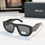 Sunglasses with black frames and dark gray lenses, Prada logo on temple