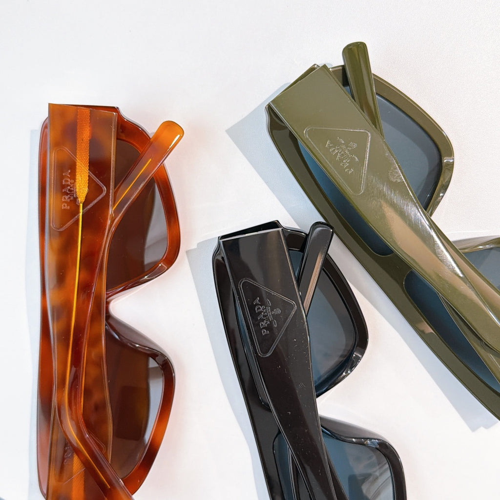 Prada sunglasses with orange, olive, and black frames and tinted lenses