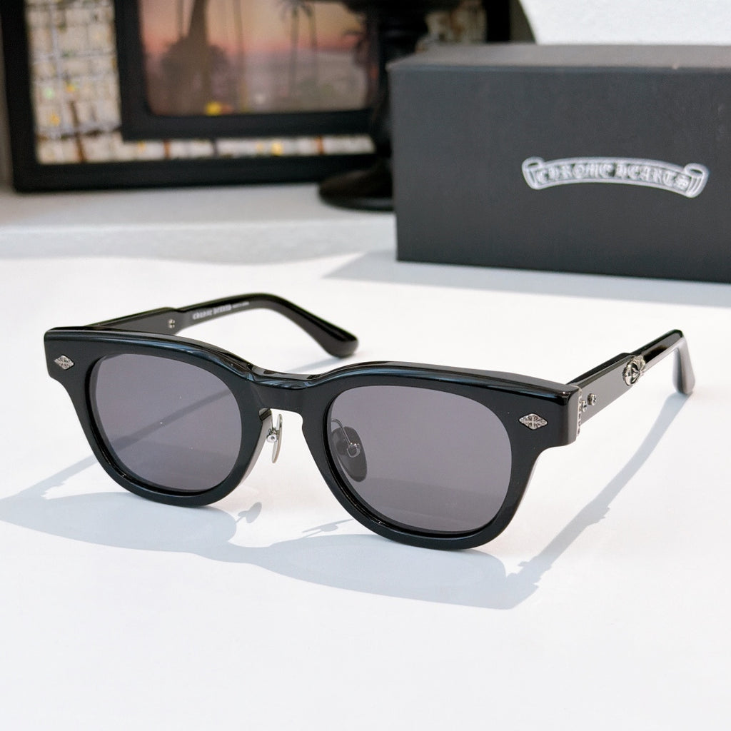 Oval sunglasses with black frame and dark gray tinted lenses, metal temples and arms.