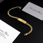 Dior gold-tone chain bracelet with textured bar charm and D clasp closure.