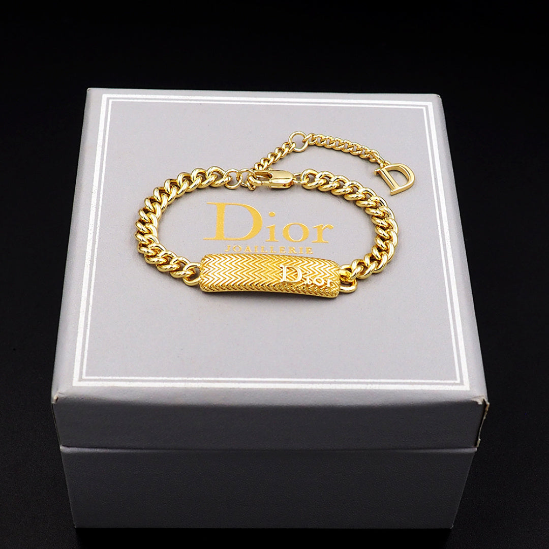 Dior gold-tone chain bracelet with textured bar charm and D clasp on box lid.