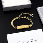 Dior gold-tone chain bracelet with textured bar charm and D clasp closure.